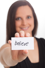 Believe! Smiling female holding card up.