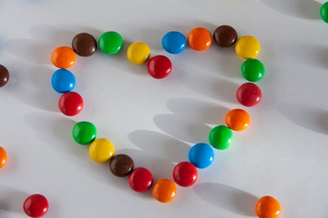 Love and Valentines Day concept.Multicolored chocolate dragees are laid out in the shape of a heart.
