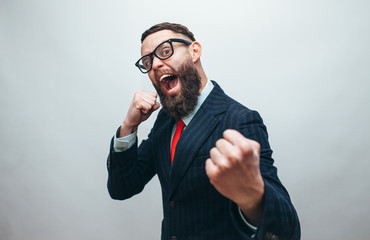 Crazy businessman with beard in trendy formal suit ready for fight over gray background
