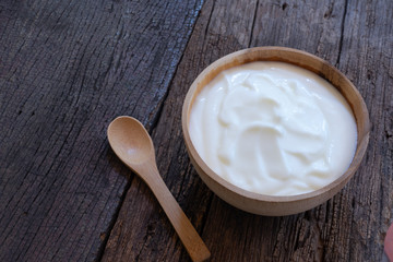 Natural homemade plain organic yogurt in wood bowl on wood texture background