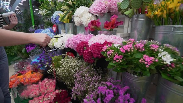 People choose flowers in a flower shop in the refrigerator at a display stand