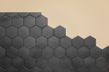Hexagonal black tile on a light wall. Copy space.