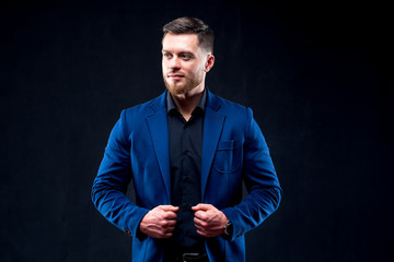 Portrait of a sexy muscular young man over black background. Men's beauty, fashion.