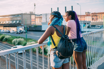 Two young beautiful black sisters outdoor posing looking over