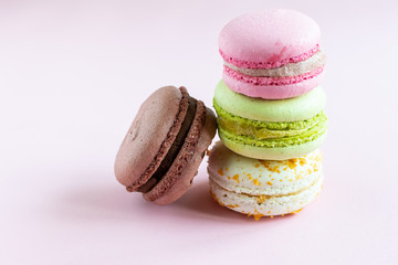 Colorful French macaroons on light pink background close up. Healthy homemade dessert.