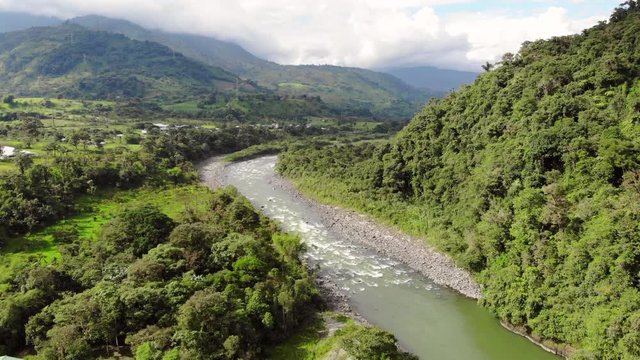 View above the Rio Quijos Valley, a tributary of the Amazon in Ecuador, view downstream showing the Baeza-Lago Agrio road and areas cleared for cattle pasture. Tilt shot.