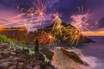 Women Standing With fireworks over the Sunset Beach