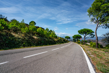 Empty long mountain road to the horizon on a sunny summer day at bright sunset