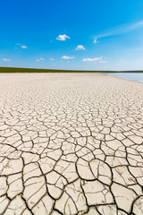 The dry cracked soil on the coast of the salt lake in the bright sunny day. Gruzskoe lake, Rostov-on-Don region, Russia