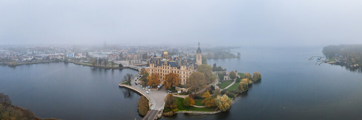 Fototapeta na wymiar Panorama aerial lake view of Schwerin Castle Palace with heavy fog and haze in the morning