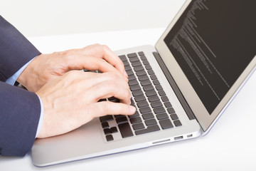 Caucasian male in suit typing something on laptop - studio shot