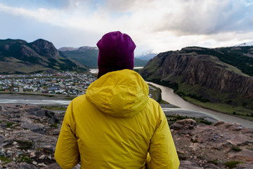 Alone hiker with yellow jacket admiring views over El Chalten village. Patagonia, Argentina