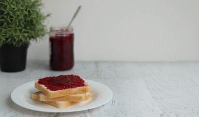 Toast with raspberry jam on a white table, space for text