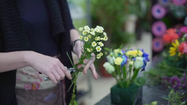 Florist girl makes a bouquet of flowers in a flower shop, hands closeup. Fower sale