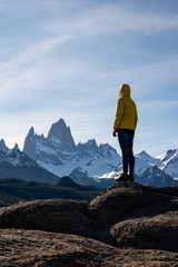 Alone hiker with yellow jacket admiring views over Mount Fitz Roy on the Andes. Patagonia, Argentina