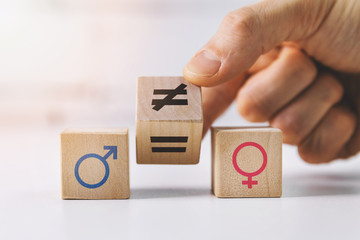 gender equality and discrimination concept - hand putting wooden blocks with symbols - obrazy, fototapety, plakaty