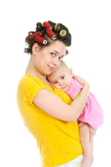 A young mother in curlers smiles, holds her baby daughter in her arms, and gently hugs , isolated at white background