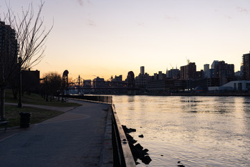 Fototapeta na wymiar Empty Waterfront at Rainey Park in Astoria Queens New York along the East River with a view of Roosevelt Island and the Manhattan Skyline during Sunset