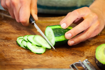 Female hands cut a courgette into small slices