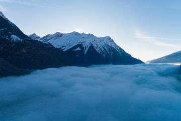 Fototapeta na wymiar Top of snowy mountains with fog underneath