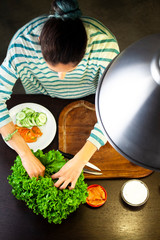Woman prepares salad on the kitchen table, flat lay