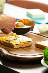 Woman prepares a toast with salmon, zucchini and avocado cheese