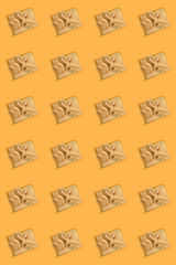 Vertical seamless pattern of gift boxes, trendy wrapped in golden fabric in Furoshiki technique on yellow background.
