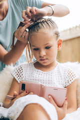 Naklejka premium Mother do hair braid to her daughter, close up photo