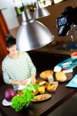 Camera shoots a woman preparing salad in the kitchen