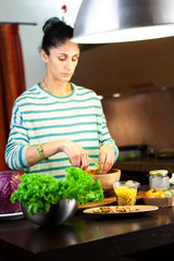 Woman prepares a bowl of mixed salad in the kitchen