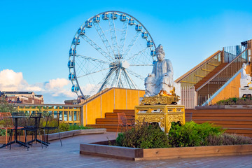 Helsinki. Finland. Buddha statue on the background of the Ferris wheel. The Ferris wheel in the Harbor of Helsinki. Sights of the capital of Finland. A journey through the Scandinavian countries.