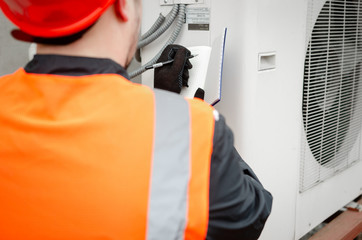 Engineer in protective workwear designing makes notes in his notebook, while standing near the...