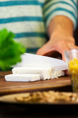 Woman cuts slices of white cheese