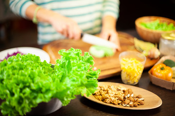 Woman prepares a vegetarian dish with salad, corn, dried fruit and cheese