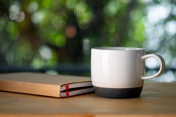 White ceramic cup and book on white table