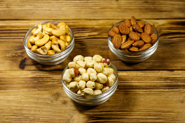 Assortment of nuts on wooden table. Almond, hazelnut and cashew in glass bowls. Healthy eating concept