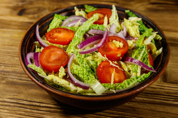 Healthy salad with savoy cabbage, cherry tomato, red onion and olive oil on wooden table