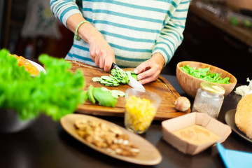 Woman cutting a courgette on the kitchen cutting board