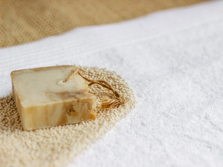 Handmade soap on a bath glove and white bath towel 