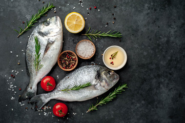 Fresh dorado fish with spices and ingredients tomato, razmorin, sunflower oil, lemon for cooking on a stone background with copy space for your text