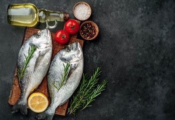 Fresh dorado fish with spices and ingredients tomato, razmorin, sunflower oil, lemon for cooking on a stone background with copy space for your text