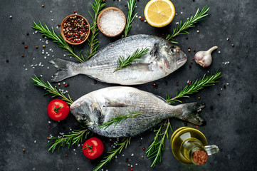 Fresh dorado fish with spices and ingredients tomato, razmorin, sunflower oil, lemon for cooking on a stone background