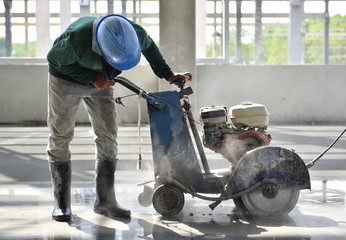 Workers using machine cutting concrete for expansion and isolation joint of slab on grade in...