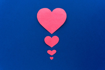 Decorative paper pink hearts flat lay at dark blue background. Valentine day concept.
