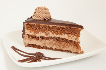 Slice of chocolate cake with decoration on white plate
