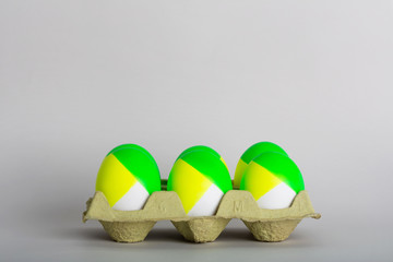 Six Easter colored eggs in a tray on gray background