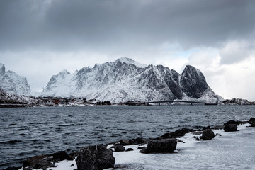 Snowy mountain with fishing village in gloomy at Lofoten islands