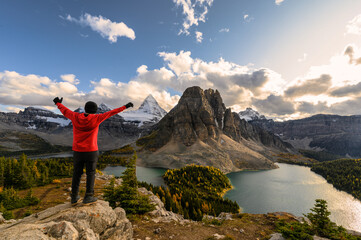Man traveler stand with raised hands on Niblet with Mount Assiniboine in provincial park