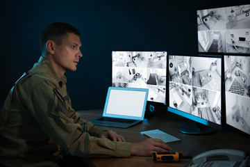 Security guard monitoring modern CCTV cameras in office