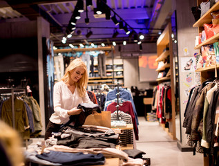 Beautiful young woman with shopping bags standing at the clothing store